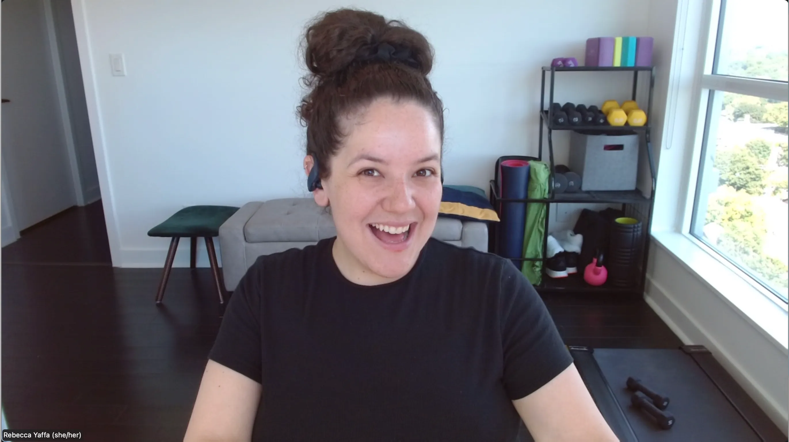 Rebecca Yaffa smiling during a virtual personal training session on Zoom, in her home workout space.